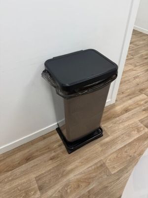 une poubelle noire posée à côté des toilettes dans une salle de bains