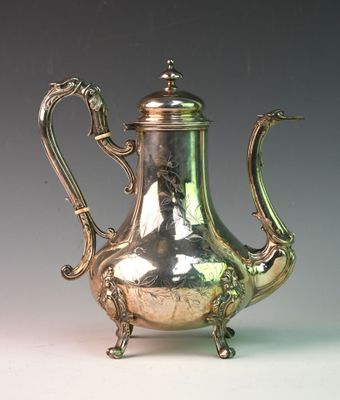 a silver tea pot sitting on a stand on a table