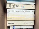 many books in a box that are stacked on top of each other