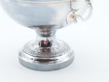 a silver cup with a handle on a white surface