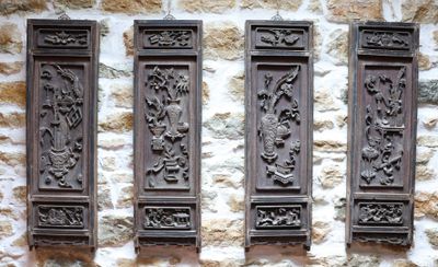 trois plaques en bois fixées au mur d'un bâtiment en pierre