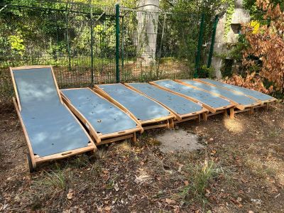 une rangée de chaises longues en bois dans la cour