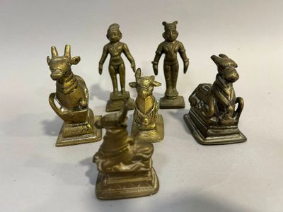 plusieurs figurines en laiton représentant des animaux et des personnages, posées sur une surface blanche