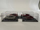 two model cars in clear boxes on a white surface