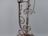 an old iron stand with a candle holder on top of it