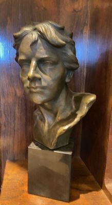 two bronze busts of men sitting on a wooden shelf
