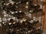bottles of wine are stacked on a metal rack in a wine cellar