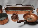beaucoup de casseroles et poêles en cuivre posées sur une table