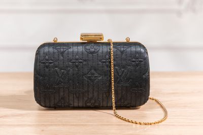 a black clutch bag sitting on top of a wooden table