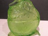un récipient en verre vert muni d'un couvercle, posé sur une table