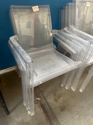 plusieurs chaises en plastique transparent empilées les unes sur les autres dans une pièce