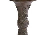 un vase en bronze posé sur une surface blanche