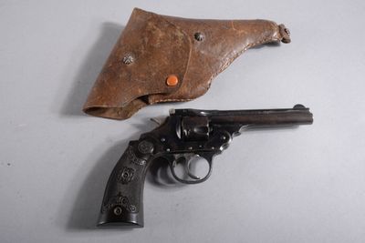 un vieux revolver dans un étui en cuir, posé sur une surface blanche