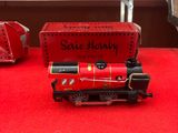 une table rouge sur laquelle se trouve un train et d'autres trains miniatures