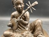 a bronze statue of a woman playing a musical instrument