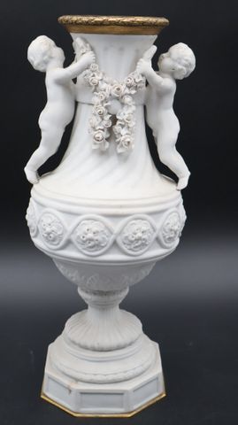 Vase en biscuit de forme balustre à décor de putti tenant des gui...