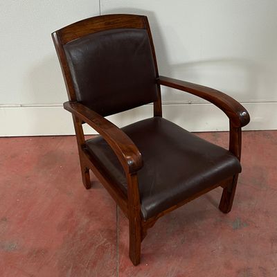 un fauteuil en cuir marron posé sur un sol rouge