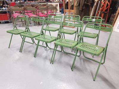 de nombreuses chaises pliantes vertes dans une pièce où se trouvent des chaises roses