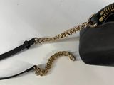 black leather purse with gold zipper and chain on white surface
