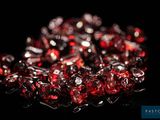 un gros plan sur un bouquet de perles de verre rouges posées sur une surface noire