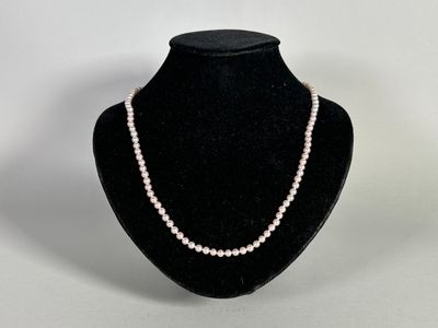 a white pearl necklace on a black mannequin