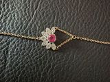 a gold chain bracelet with a pink stone flower on it