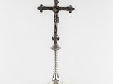 a silver cross on a pedestal with a green base