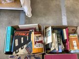 a box full of books on the floor next to a bed