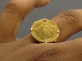 quelqu'un tient une pièce d'or dans la main et celle-ci est posée sur son doigt