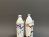 deux vases blancs ornés de motifs floraux, placés l'un à côté de l'autre