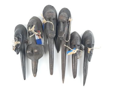 six black carved elephant heads hanging from a rope on a white wall