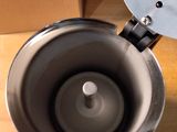 a silver coffee pot sitting on a table next to a cardboard box