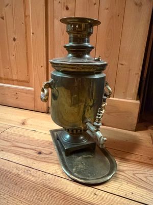 a metal coffee urn sitting on a wooden floor