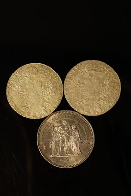 trois pièces d'or empilées les unes sur les autres sur une surface noire