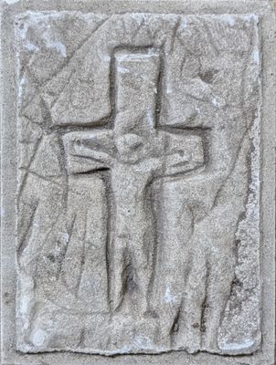 a close up of a cross on a stone wall with a person standing next to it
