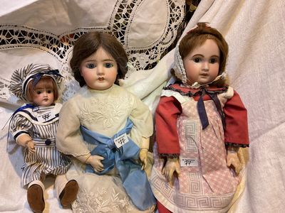 trois poupées assises l'une à côté de l'autre sur une table