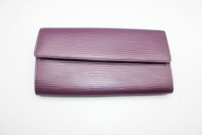un sac à main violet posé sur une table blanche