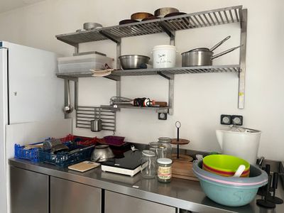 a kitchen with a stove, refrigerator, and shelves with pots and pans on it