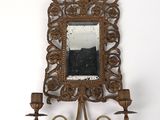 un miroir accroché au mur, sur lequel est posé un bougeoir