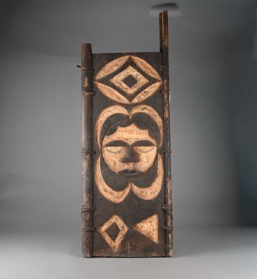 un gros plan sur une plaque en bois sur laquelle est représenté un visage