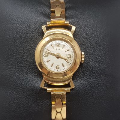 une photo en gros plan d'une montre-bracelet en or posée sur un sac noir