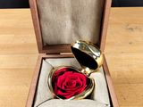 une petite boîte en bois contenant une rose rouge