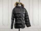La veste est noire et possède une capuche doublée de fourrure.