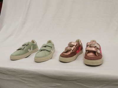trois paires de baskets sont alignées sur une surface blanche