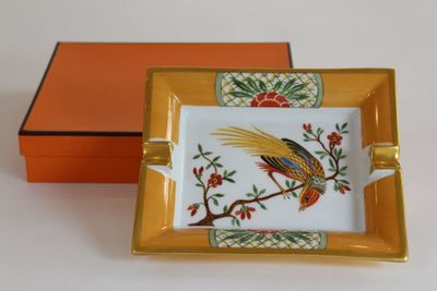un petit plateau sur lequel se trouve un oiseau, avec une boîte orange derrière