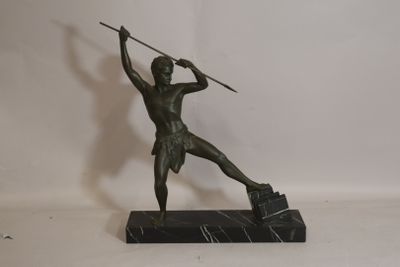 bronze statue of a man holding a spear and shield on a marble base