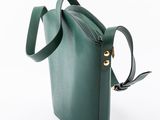 the small green bag is sitting on a white surface