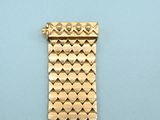 an image of a close up of a gold bracelet on a blue surface