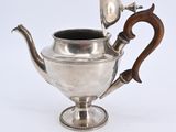 an antique silver teapot with a wooden handle on a white background