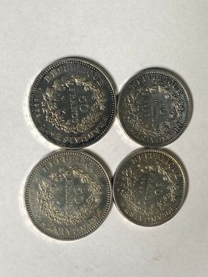 four different british coins sitting on top of a white surface
